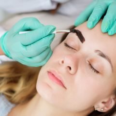 Makeup artist applies paint henna on eyebrows in a beauty salon